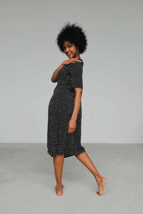 Woman in Black and White Polka Dots Dress Standing on White Floor