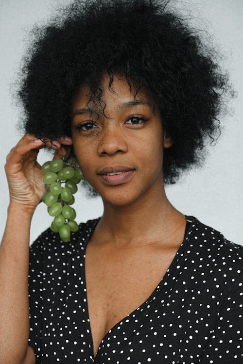 Free Woman in Black and White Polka Dot Scoop Neck Shirt Holding Green Grapes Stock Photo