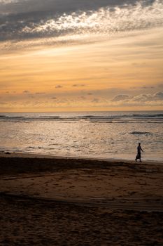 A solitary figure strolls along Casablanca's serene beach during a breathtaking sunset.