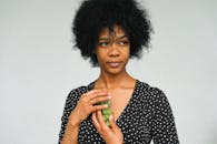 一位美丽卷发女子的特写肖像，手里拿着一串青葡萄