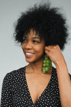 迷人的黑人女模特穿着波尔卡圆点礼服，拿着串葡萄耳环，微笑着看向镜头