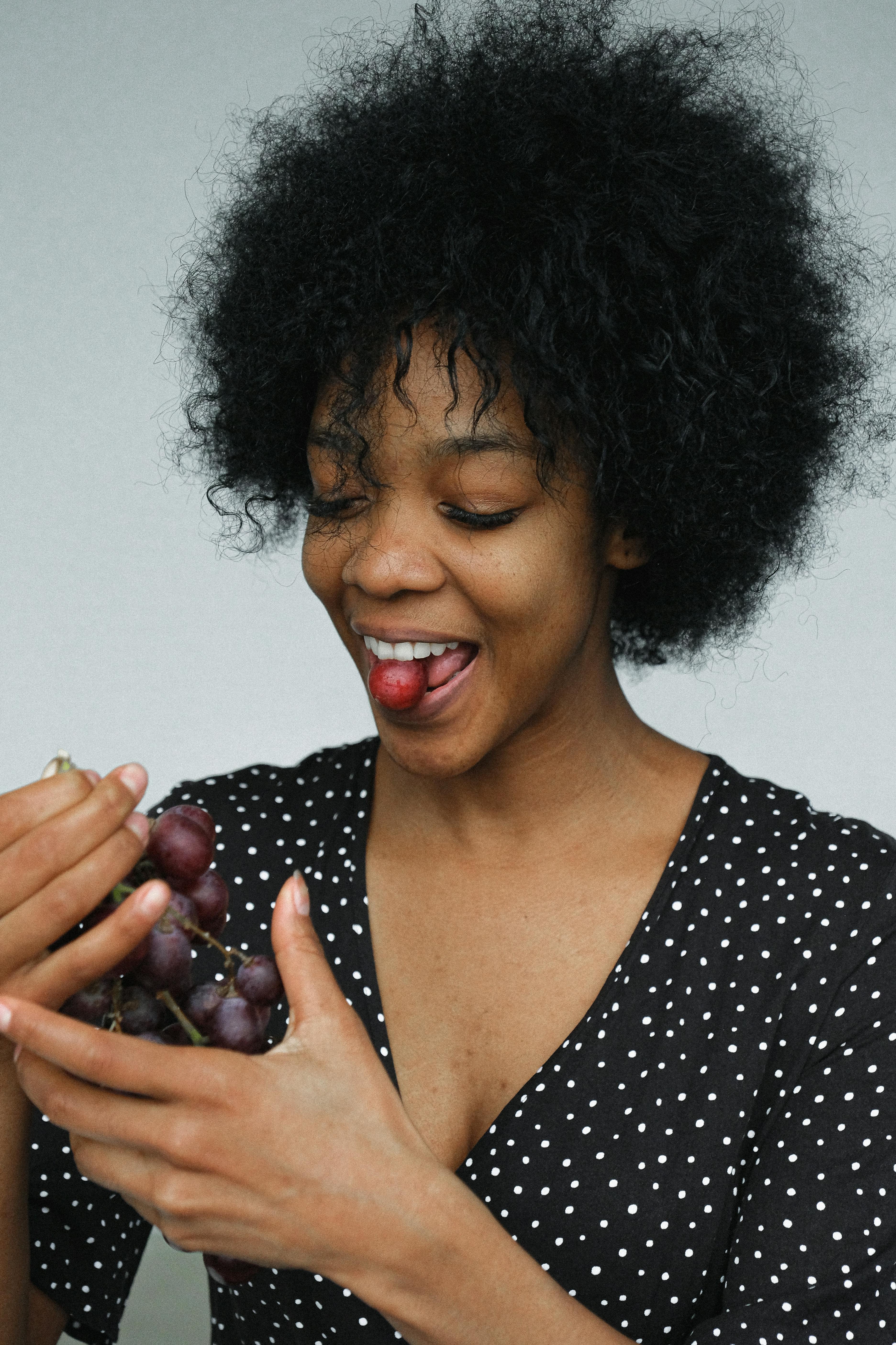 playful black woman eating grapes in studio