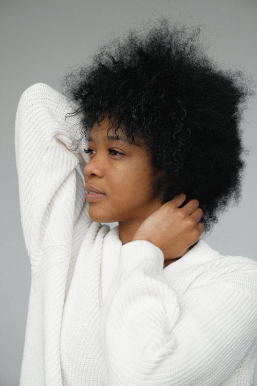 Portrait Photo of Woman in White Sweater Posing In Front of Gray Background