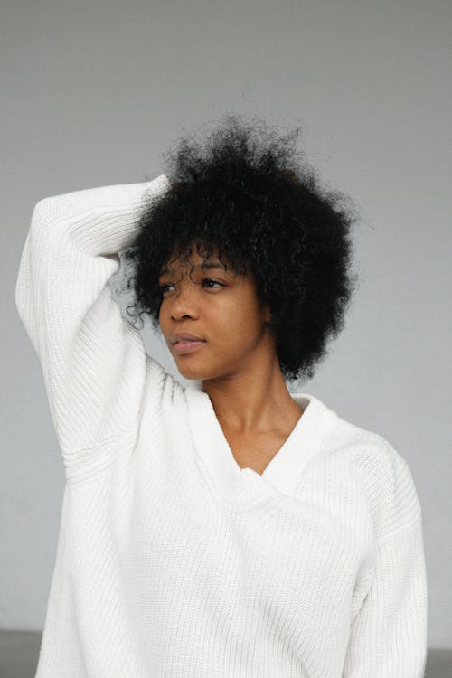 Portrait Photo of Woman in White Sweater Posing In Front of Gray Background