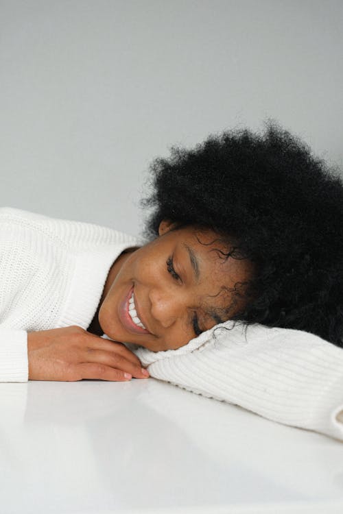 Dreaming charming black woman leaning on table