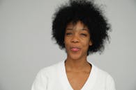 一位穿着白色毛衣、灰色背景、表情俏皮的女人的快乐肖像