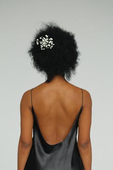 一位女士从后面走来，她戴着精致的花卉假发，身穿优雅的黑色连衣裙