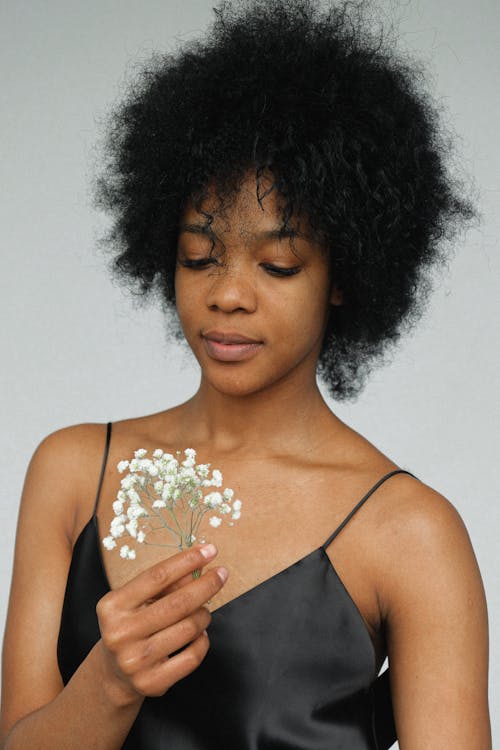 Portrait Photo of Woman in Black Spaghetti Strap Top Holding Flower