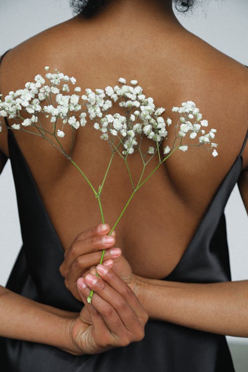 Close-up Photo of Woman in Black Night Dress Holding White Flower Behind Her Back