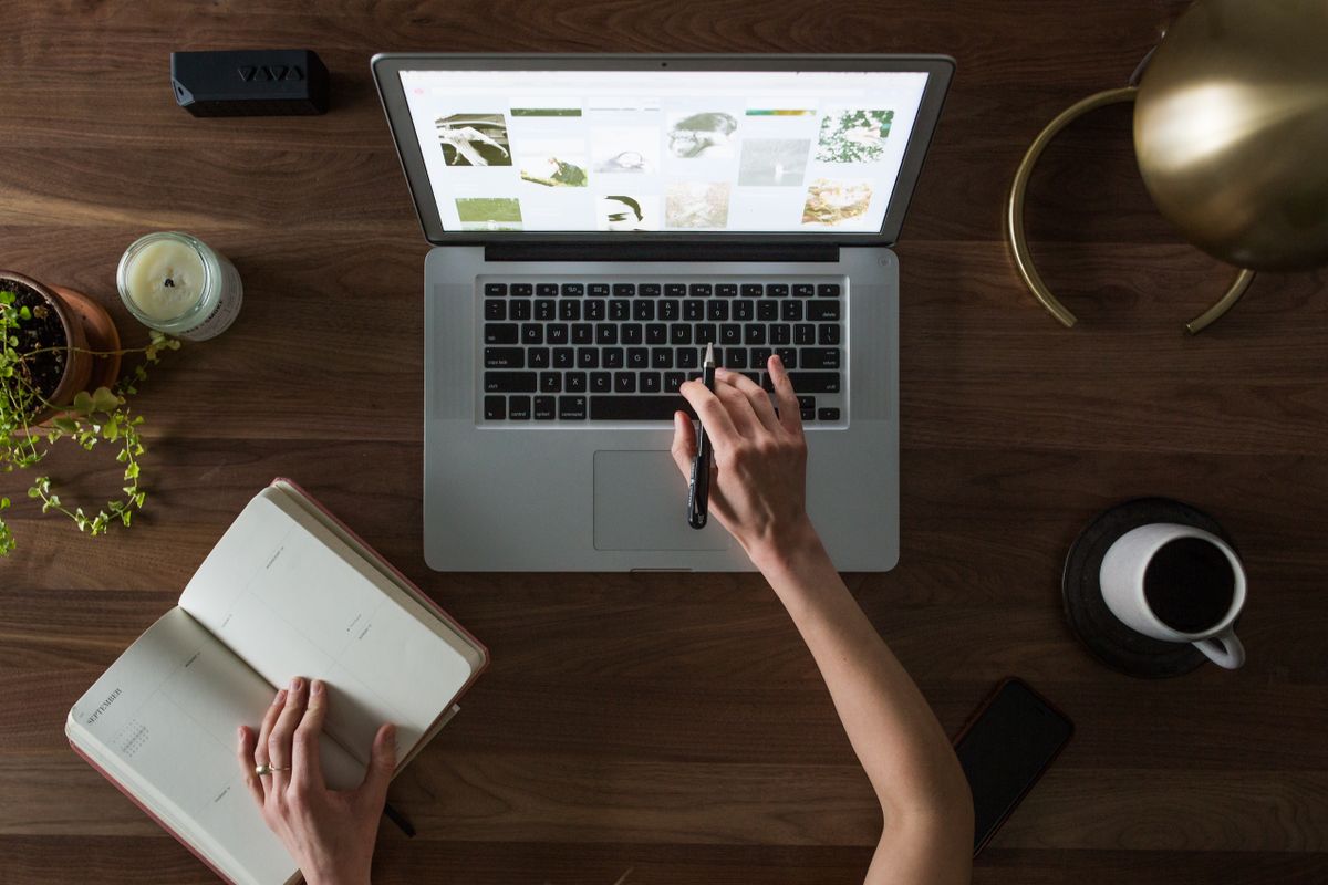 Hands on a laptop beside an open planner and coffee
