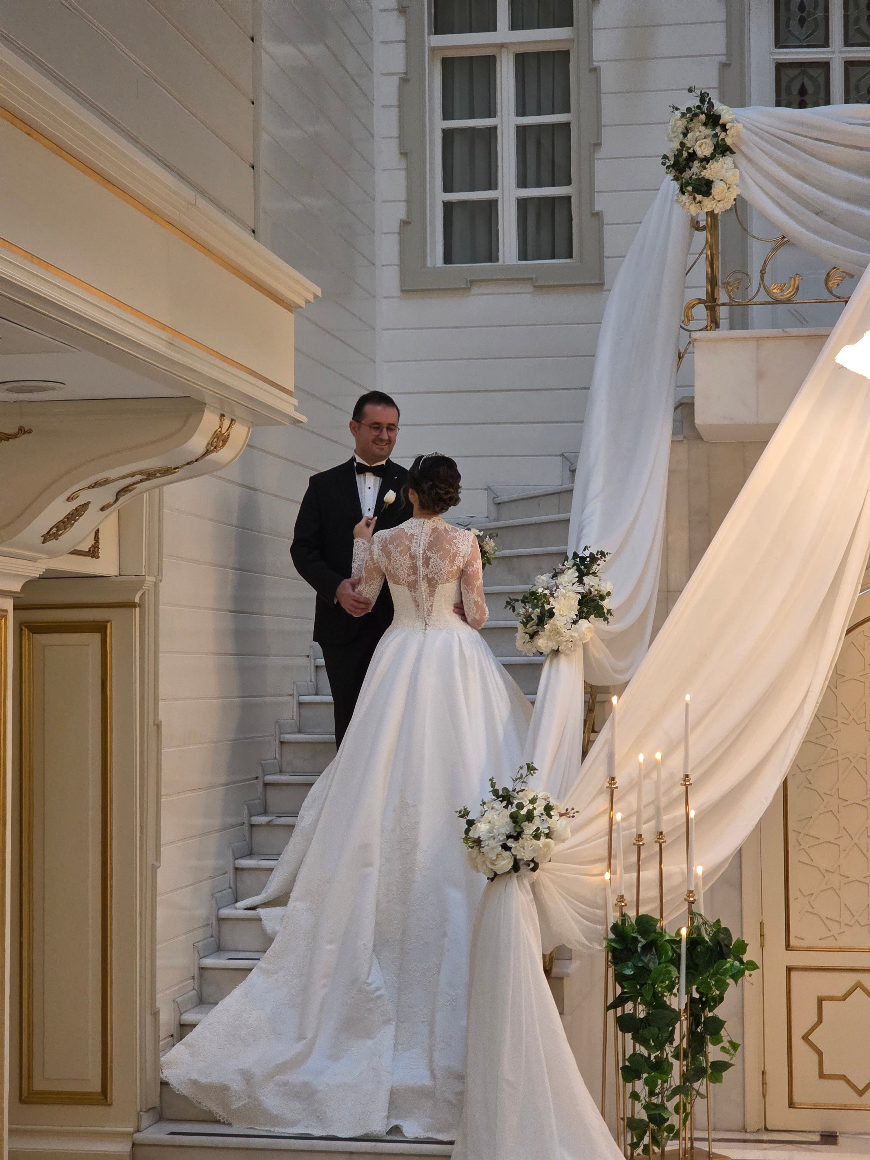 Beautiful wedding couple ascending a decorated staircase in an elegant setting, capturing romance and grace.