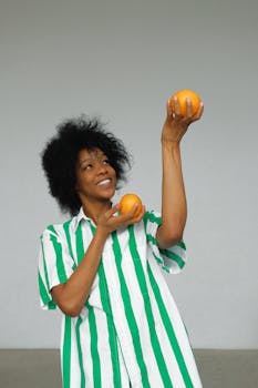 一位穿着条纹衬衫、手拿橙子的快乐非洲妇女，正在倡导室内健康生活