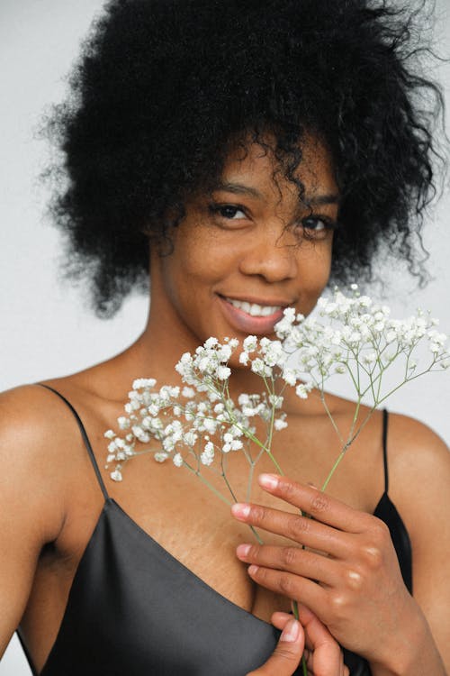 Portrait Photo of Smiling Woman in Black Spaghetti Strap Top Holding White Flower