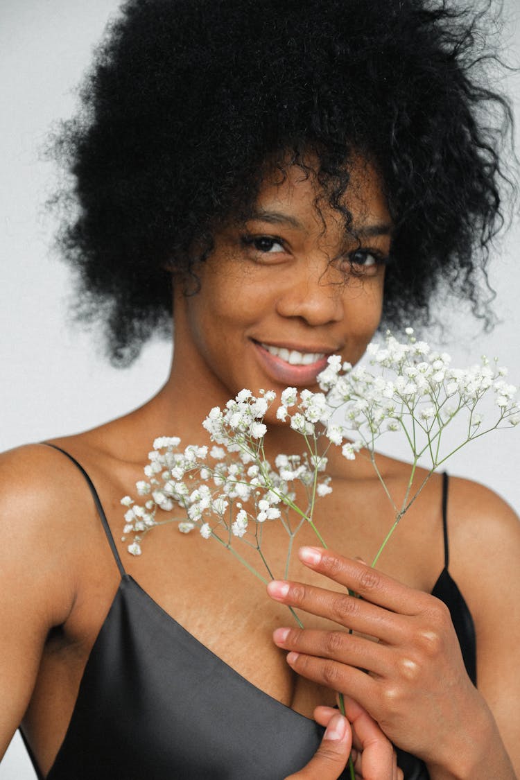 Portrait Photo Of Smiling Woman In Black Spaghetti Strap Top Holding White Flower