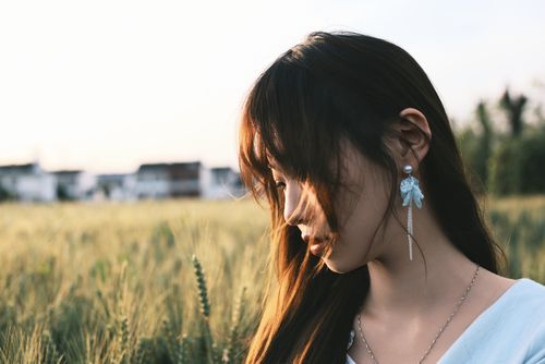 Free Young woman with long hair stands thoughtfully in a sunlit wheat field. Stock Photo