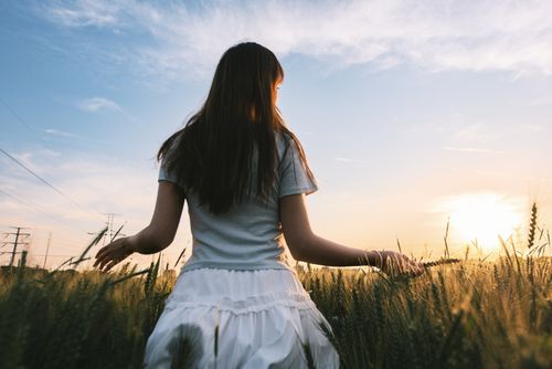 Free A woman walking through a wheat field at sunset, enjoying nature. Stock Photo