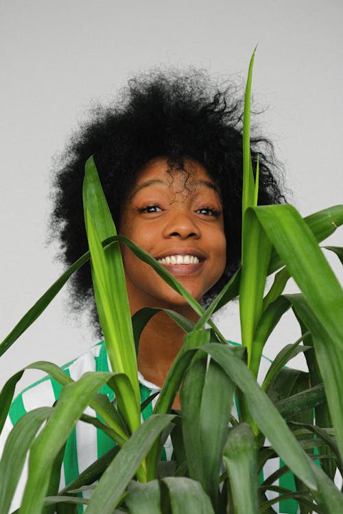 Woman Smiling Behind A Plant
