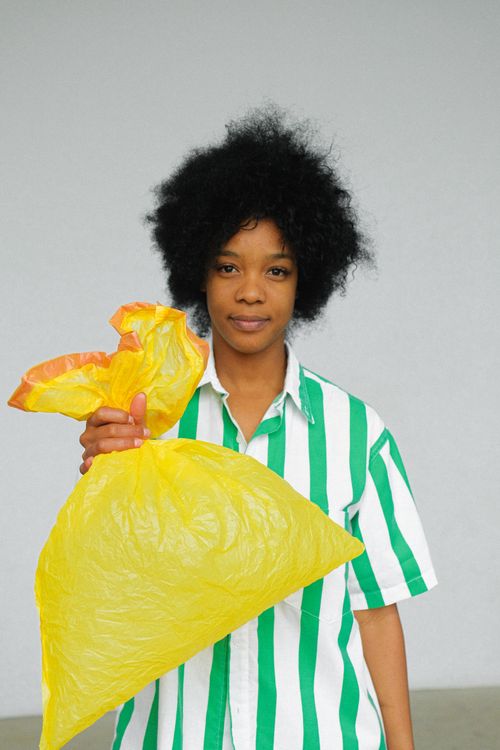 Free Portrait of a woman promoting sustainability by holding a reusable yellow bag. Stock Photo