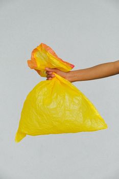 一只手拿着一个代表废物管理和回收的黄色塑料袋