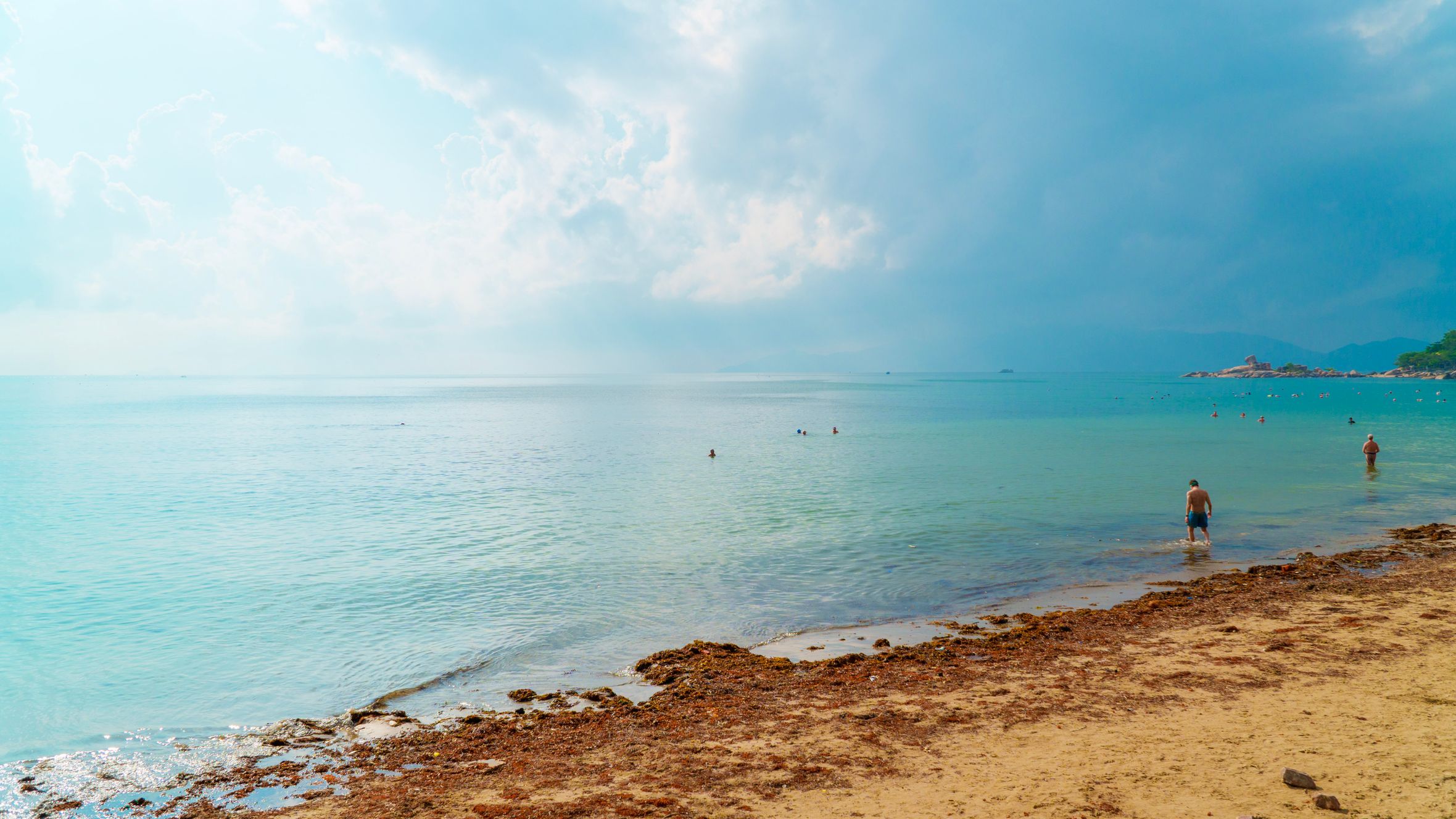 Serene beach scene at Nha Trang, Vietnam, featuring calm waters and cloudy sky.