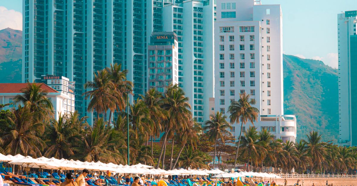 Vibrant scene of Nha Trang beach with skyscrapers, palm trees, and tourists enjoying a sunny day.