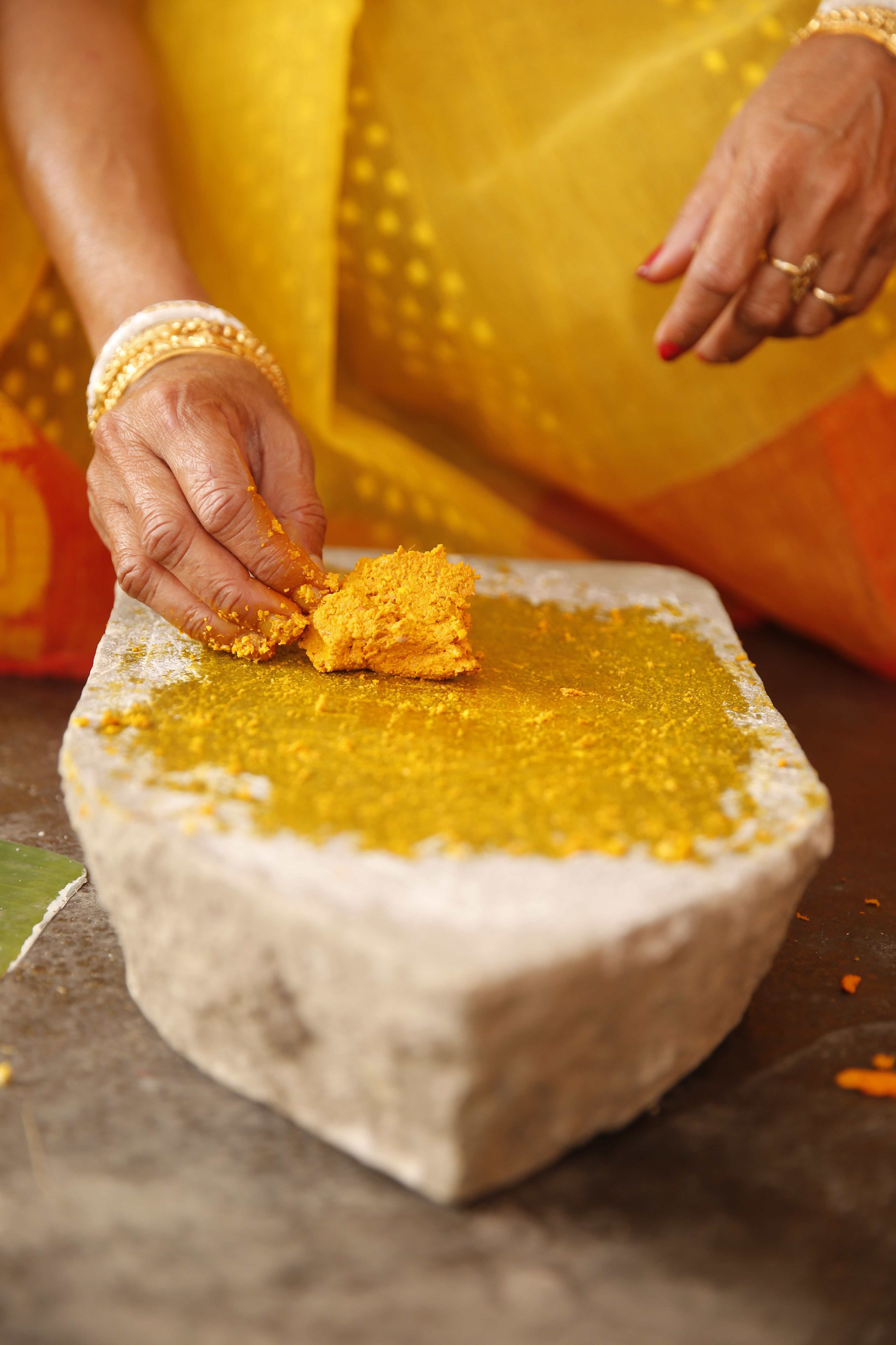 Close-up of turmeric paste preparation in a traditional South Asian wedding ceremony.