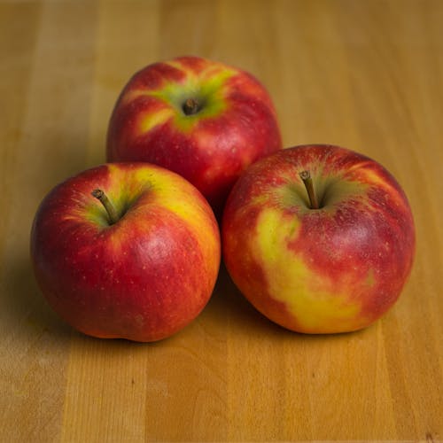 бесплатная Фрукты красного яблока на коричневом деревянном столе Стоковое фото