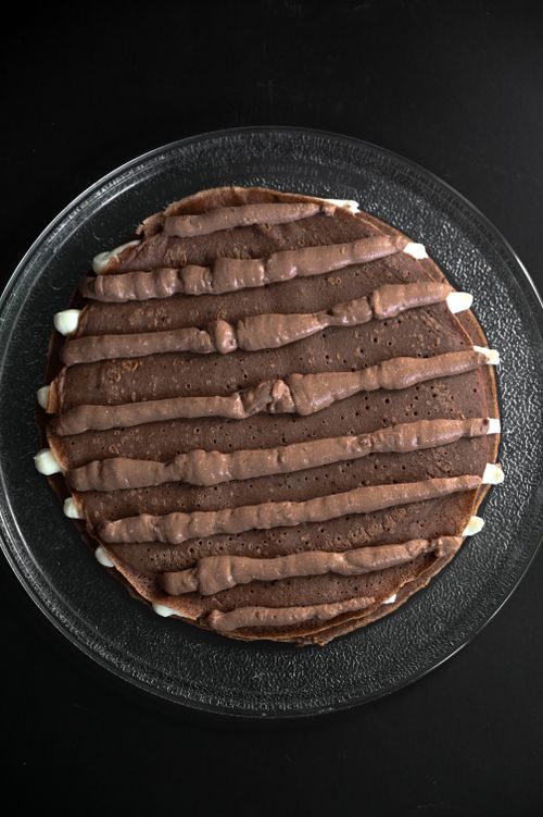 Free A mouth-watering chocolate pancake with cream topping on a glass plate, perfect for dessert. Stock Photo