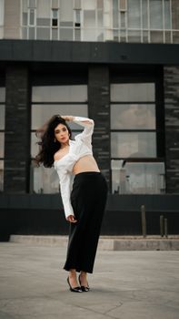 A fashionable woman poses confidently against a modern building backdrop, showcasing urban style.