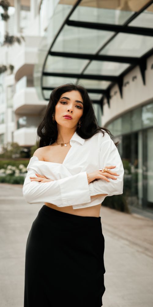 Free Confident woman in stylish attire posing outdoors with urban architecture backdrop. Stock Photo