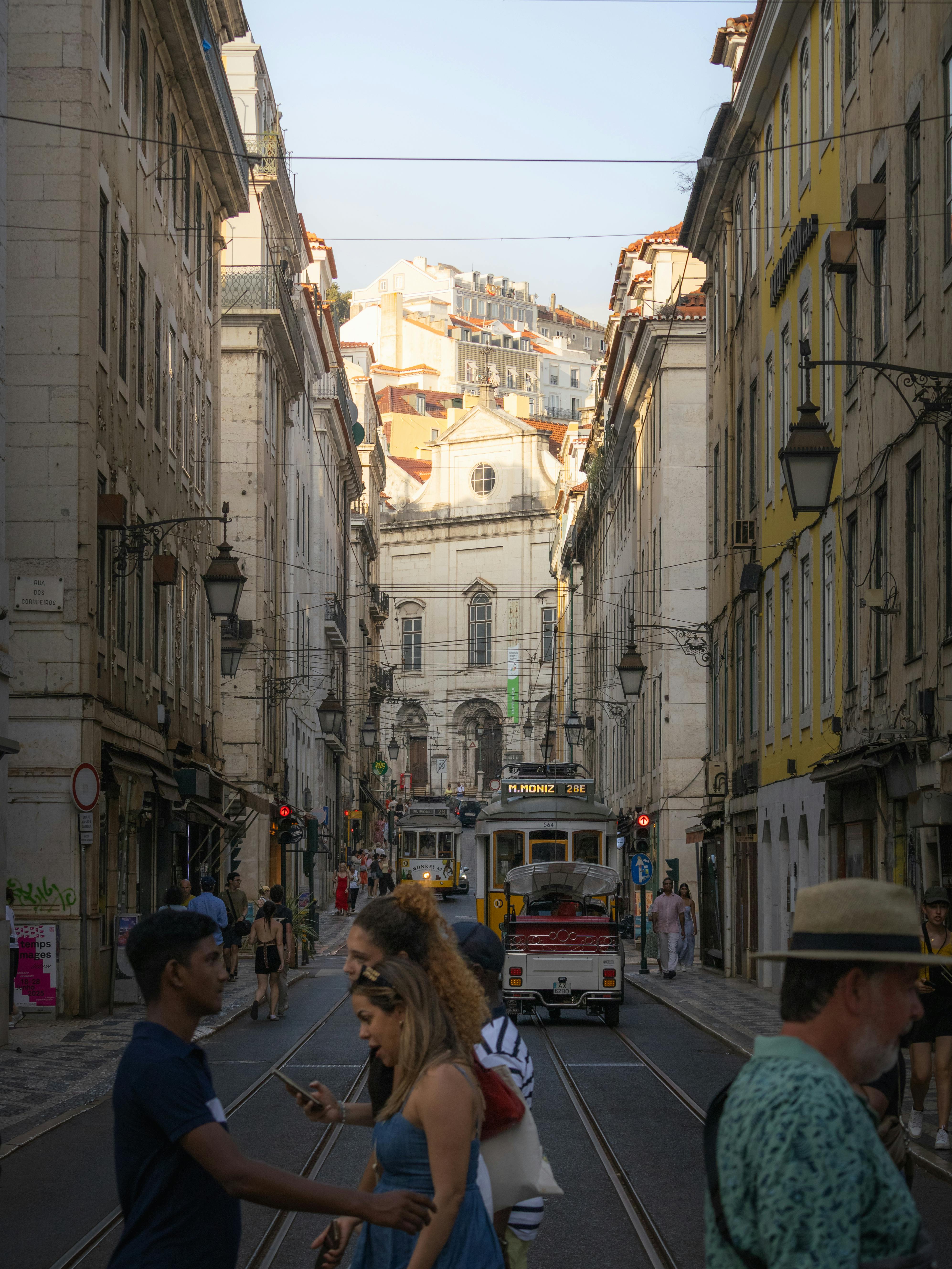 A classic tram traveling down a busy street in Lisbon, Portugal, surrounded by historic architecture.