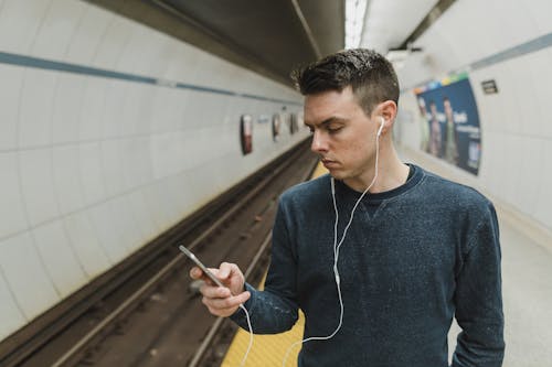 Man looking at a phone with earphones on