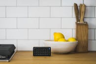 Black Portable Speaker on Top of Table Near Bowl of Lemons