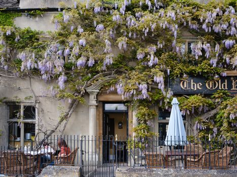 Charming wisteria-clad pub in Malmesbury, England, offering a picturesque outdoor setting.