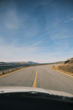 A deserted curved road in a mountainous region with a clear blue sky, perfect for travel themes.