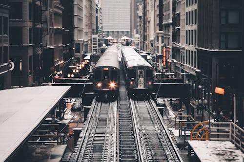 Grayscale Photography of Two Trains Beside Concrete Building