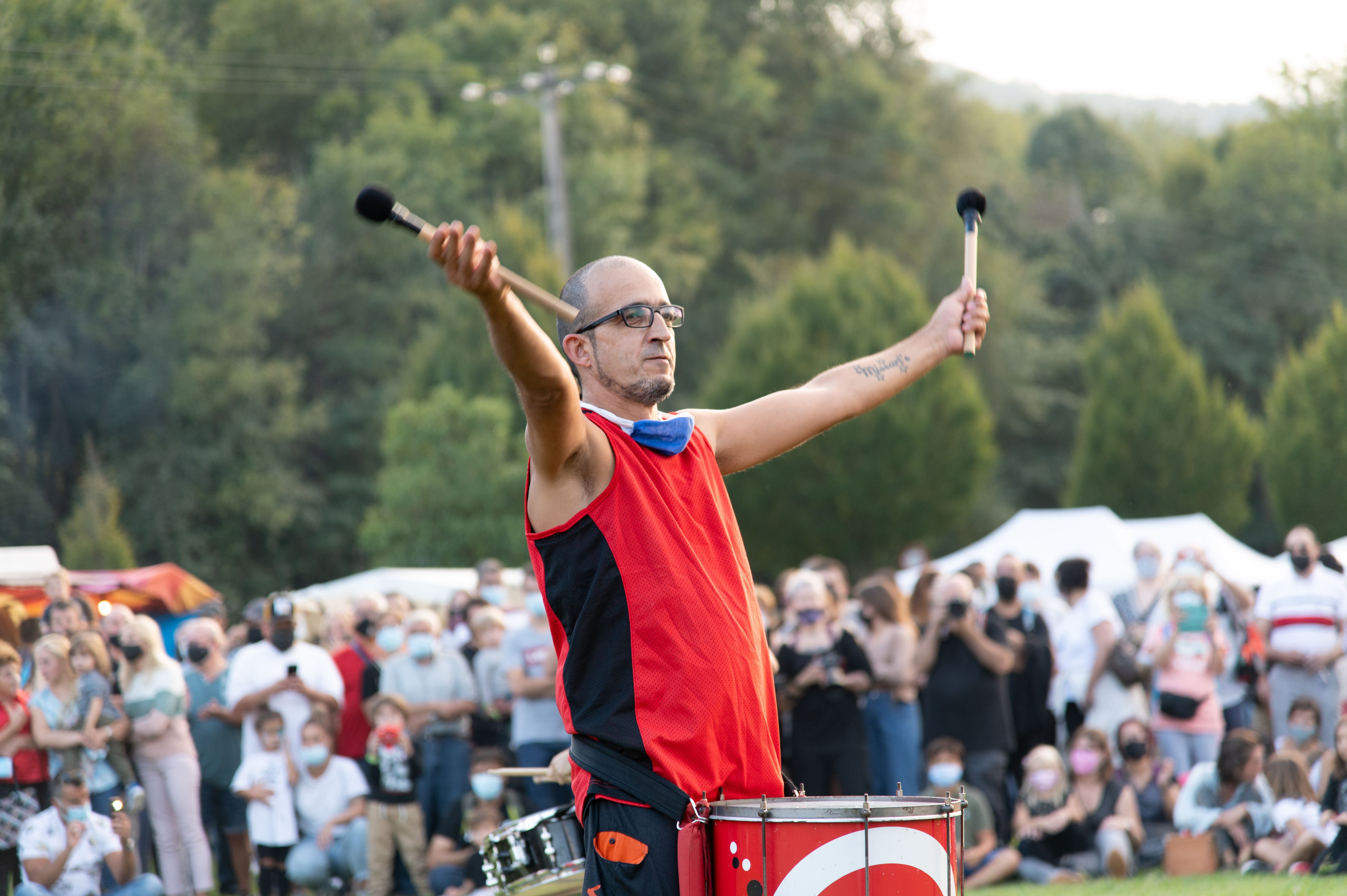 Man in red playing drums at an outdoor festival in Spain.