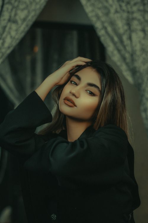 Free A stylish and moody indoor portrait of a woman in elegant attire, perfect for fashion or lifestyle themes. Stock Photo