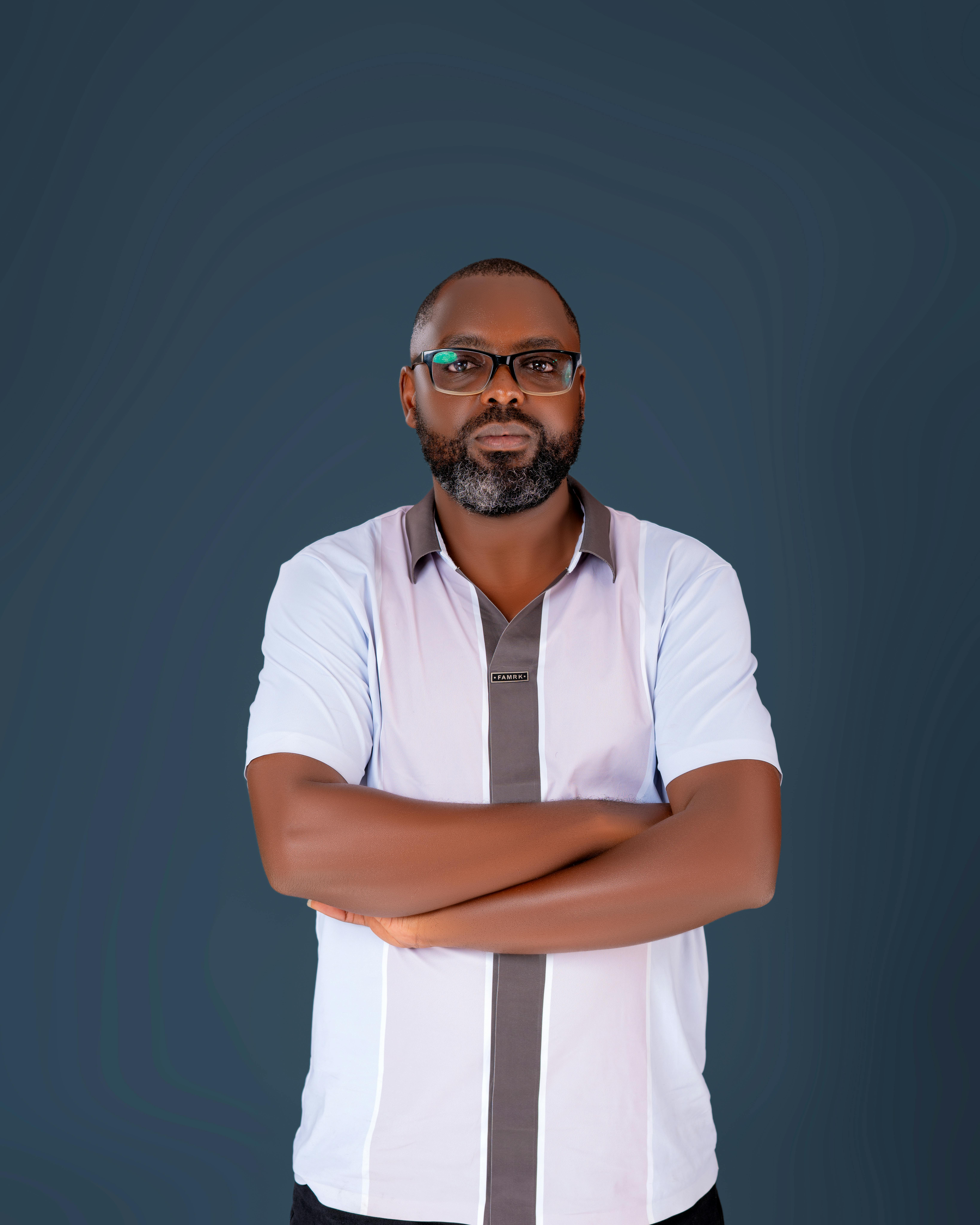 Portrait of a confident man with arms crossed against a dark backdrop, expressing strength and assurance.