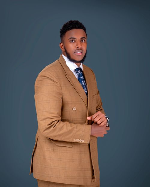 Free Confident man wearing a tan suit and patterned tie against a neutral background. Stock Photo