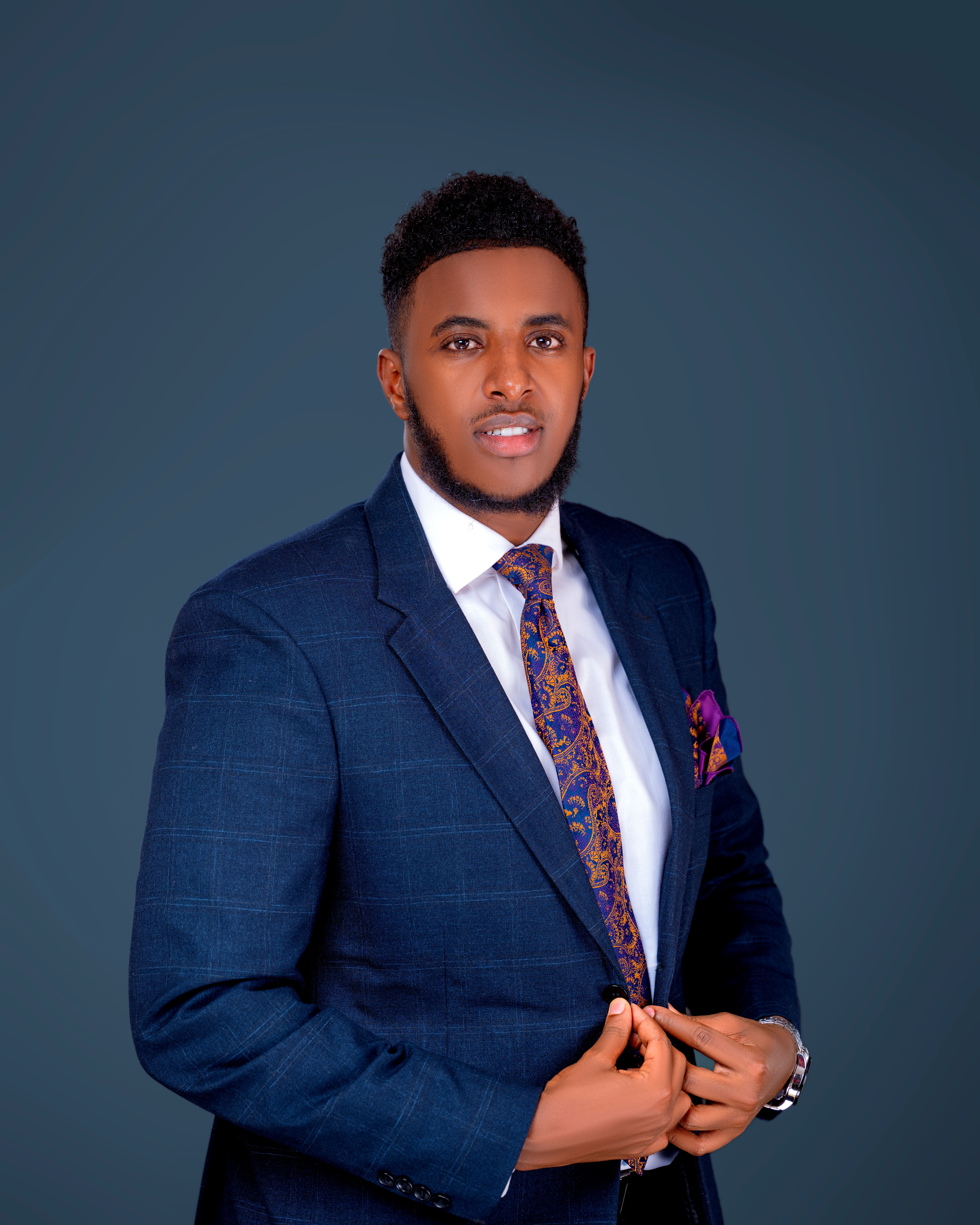 Young man in a suit posing confidently against a plain background.