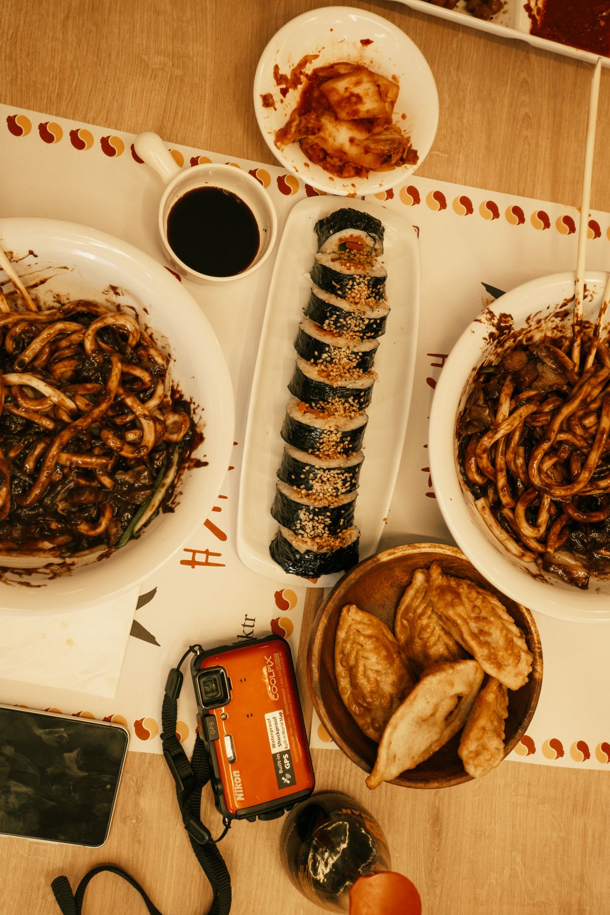 Noodles, gimbap and side dishes on a shared table. Confirm what is included with your order.