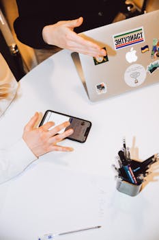 两个人在现代化的工作空间环境中，使用笔记本电脑和智能手机进行协作