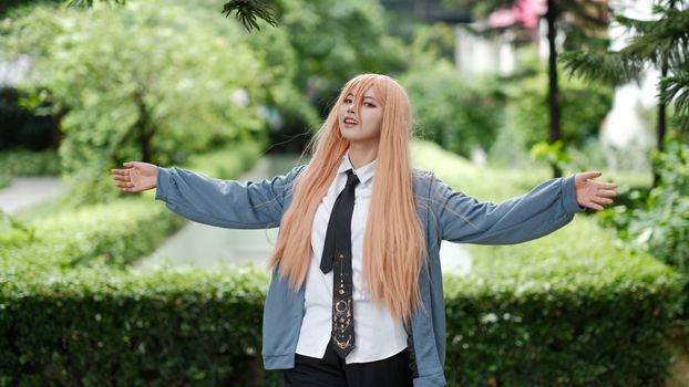 Person in cosplay with long wig posing outdoors in garden setting.