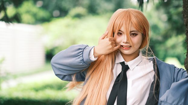 A person in cosplay costume enjoying an outdoor photoshoot with a lush green backdrop.