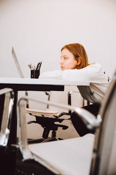 一位女士在现代办公空间中靠着桌子，显得若有所思