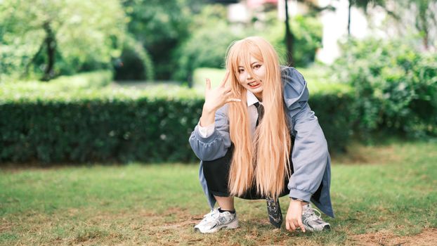 A person in cosplay attire squats in a lush green park, showcasing vibrant outdoor fashion.