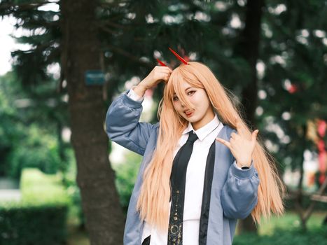 Energetic cosplayer portrays a character outdoors, showcasing long hair and horns.