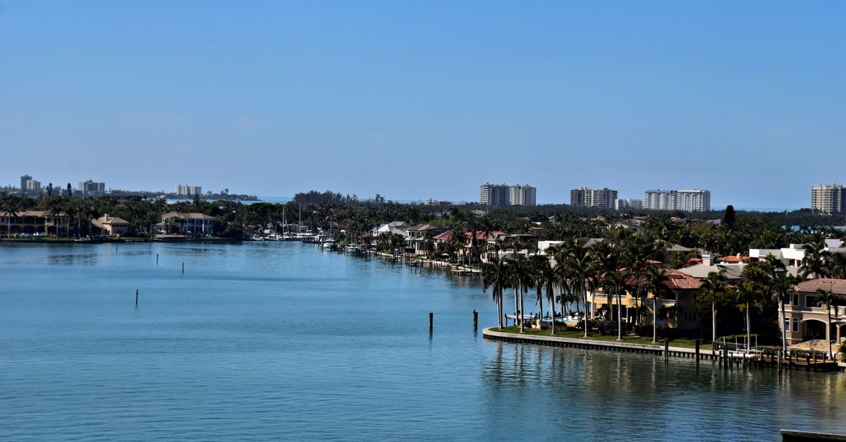 Tranquil waterfront scene of Sarasota, Florida, showcasing residential areas and clear blue skies.