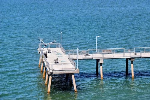 Free A peaceful pier extends over the blue waters in Sarasota, Florida, perfect for a tranquil outdoor leisure spot. Stock Photo